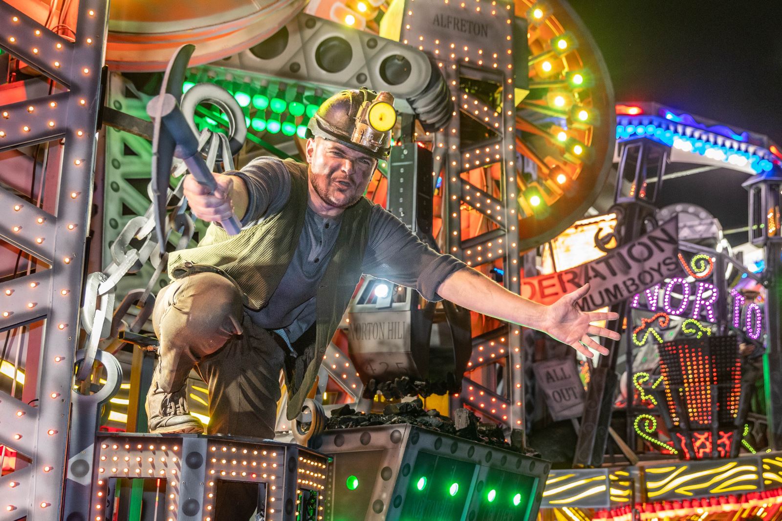 A performer on the Ramblers 1912 All Out Cart at the Weston-super-Mare Carnival leans forward wielding his mining axe